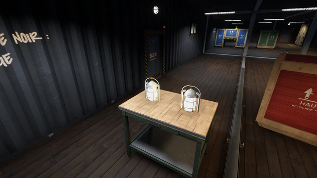 Deux lanternes allumées sur une table, dans un conteneur plongé dans le noir.